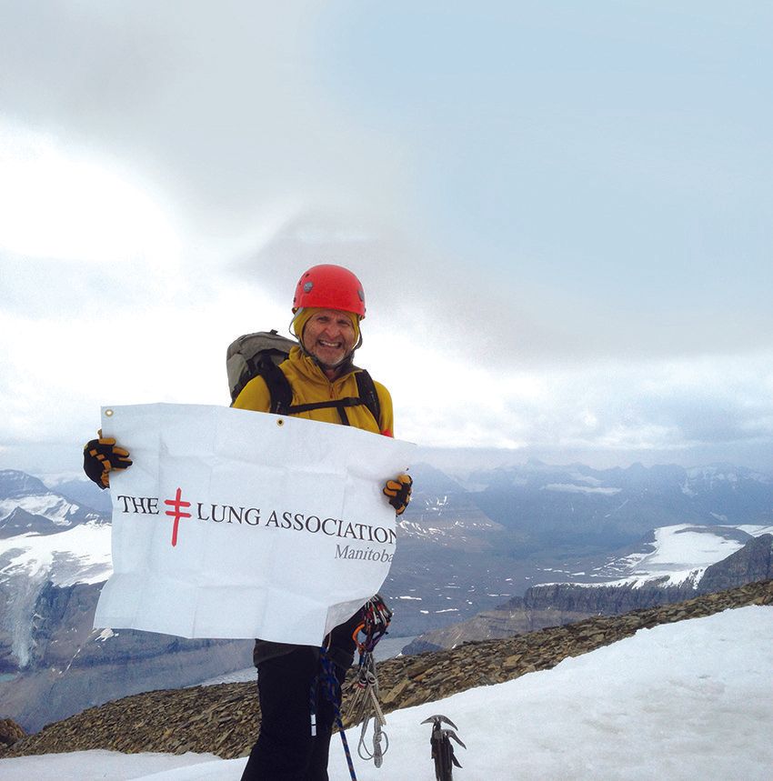 Man on snowy mountain summit holds Lung Association banner.