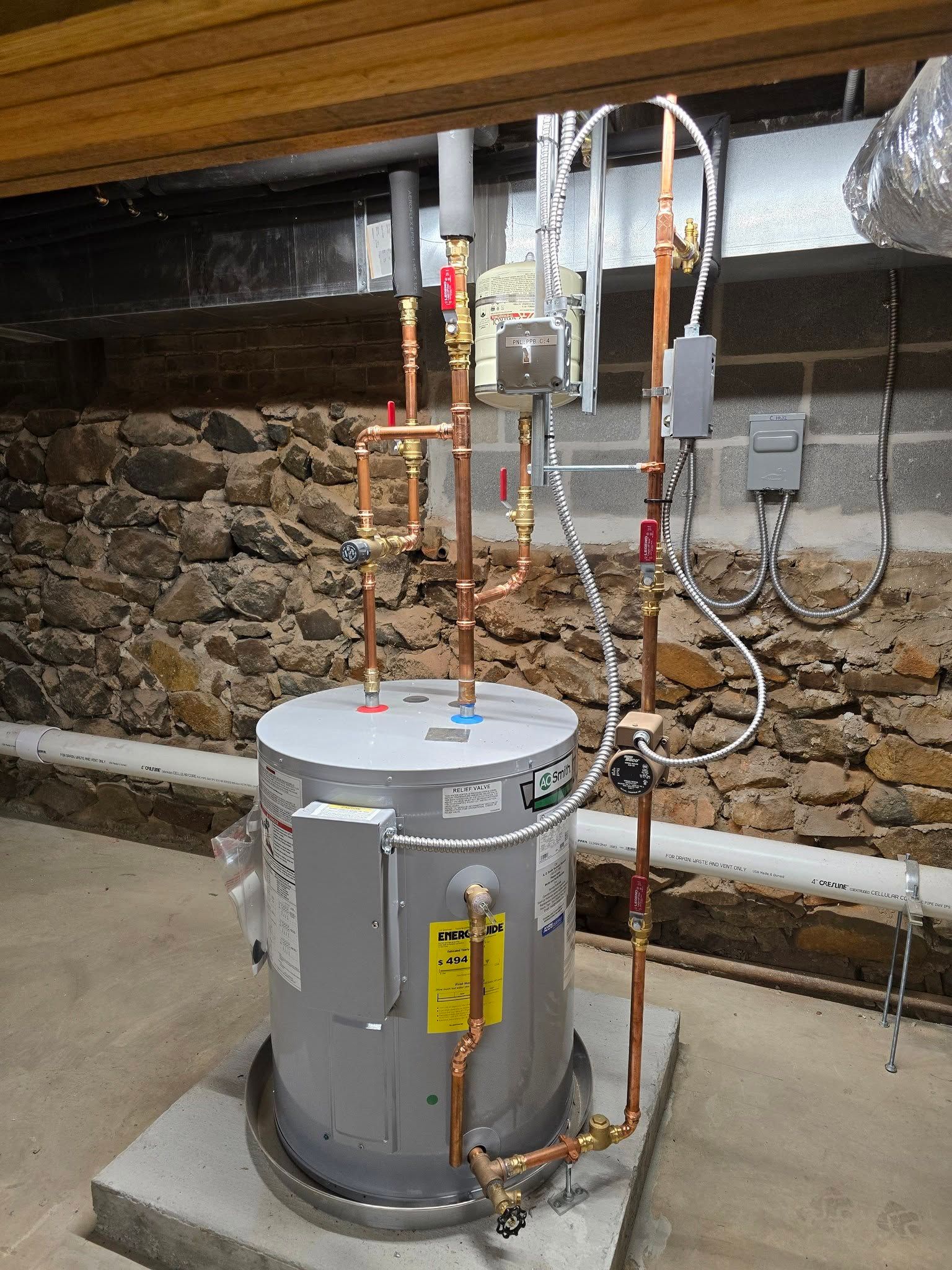 Gray water heater with copper pipes and valves in a basement utility area
