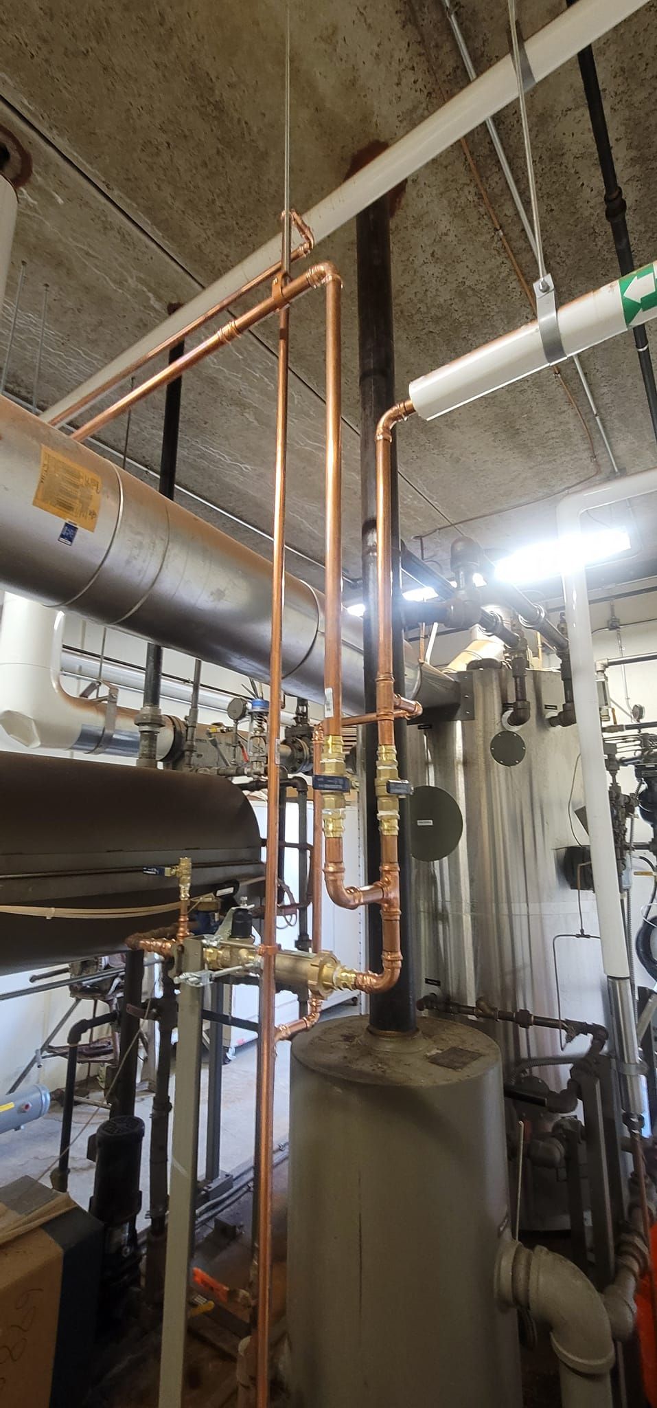 Industrial basement with copper pipes, ducts, and mechanical equipment in a utility room