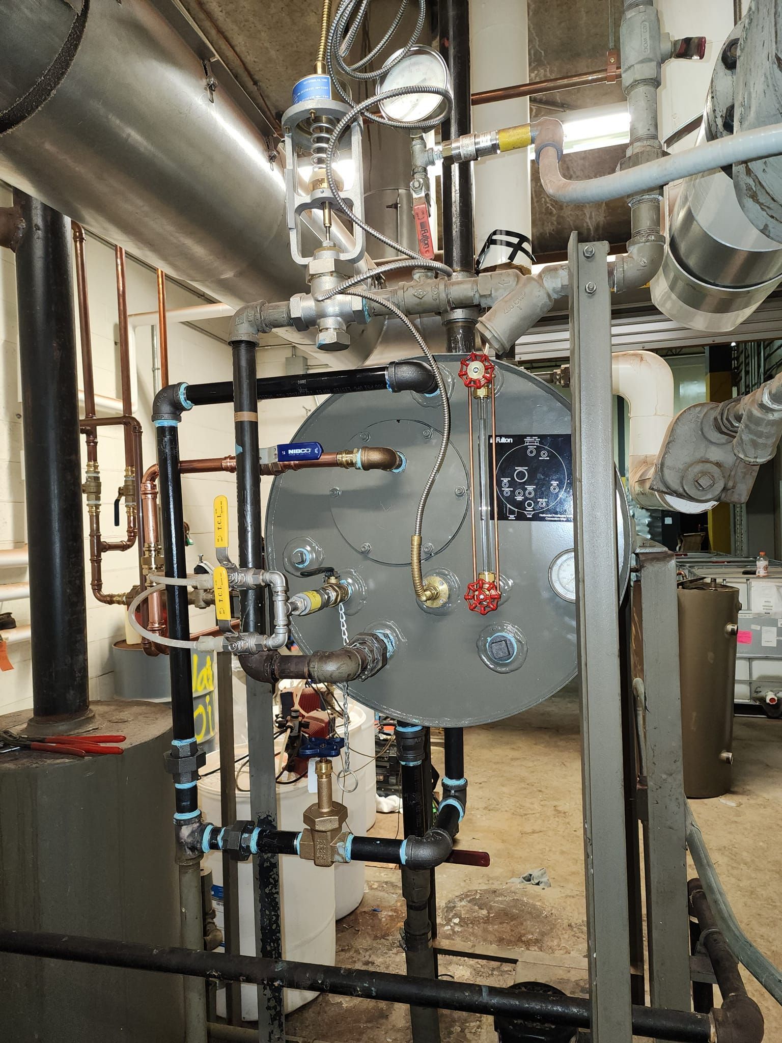 Industrial machinery with pipes, valves, and gauges in a utility room