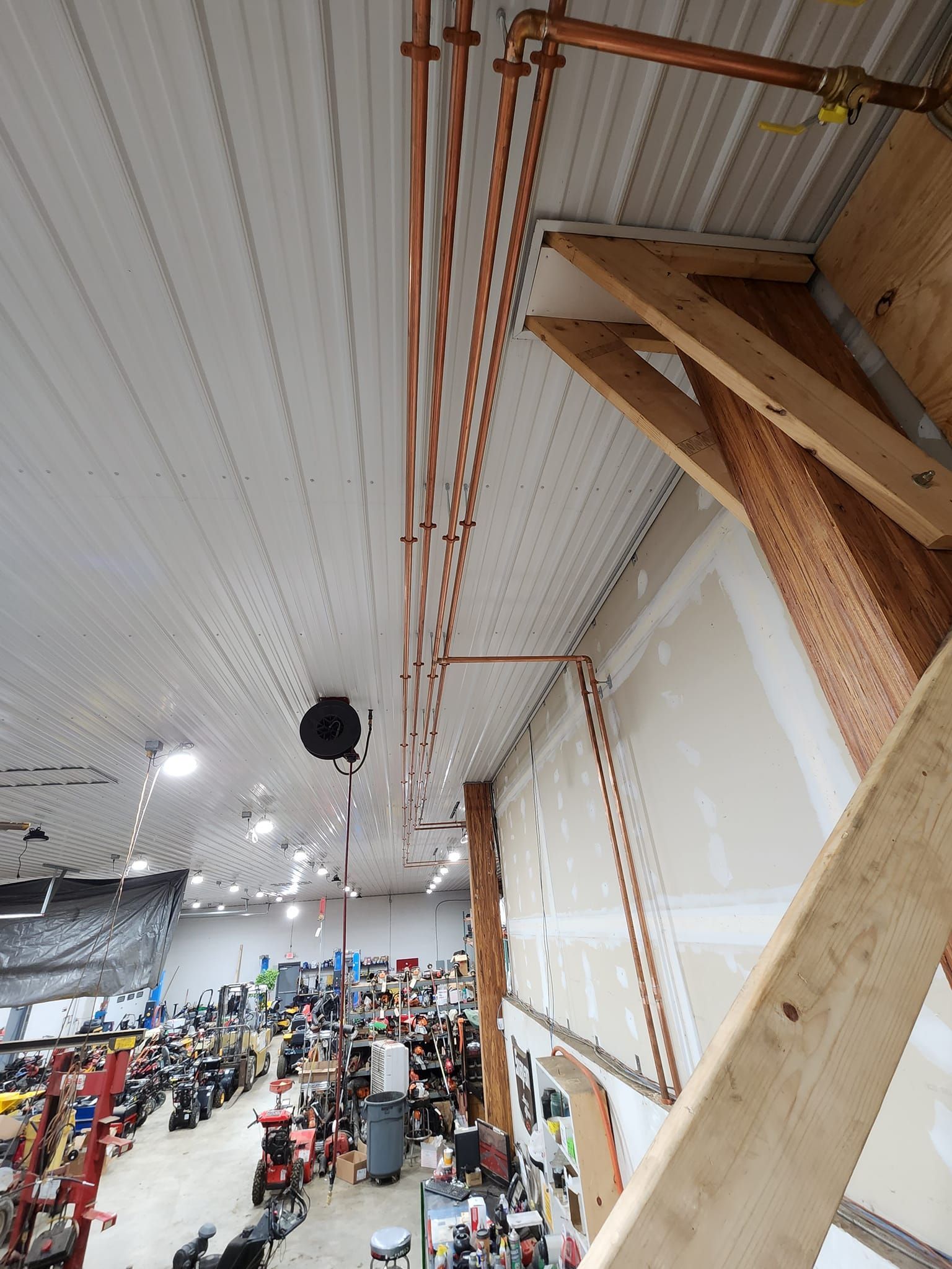 Indoor gym with white ceiling, hanging lights, and a crowd gathered below near wooden beams.
