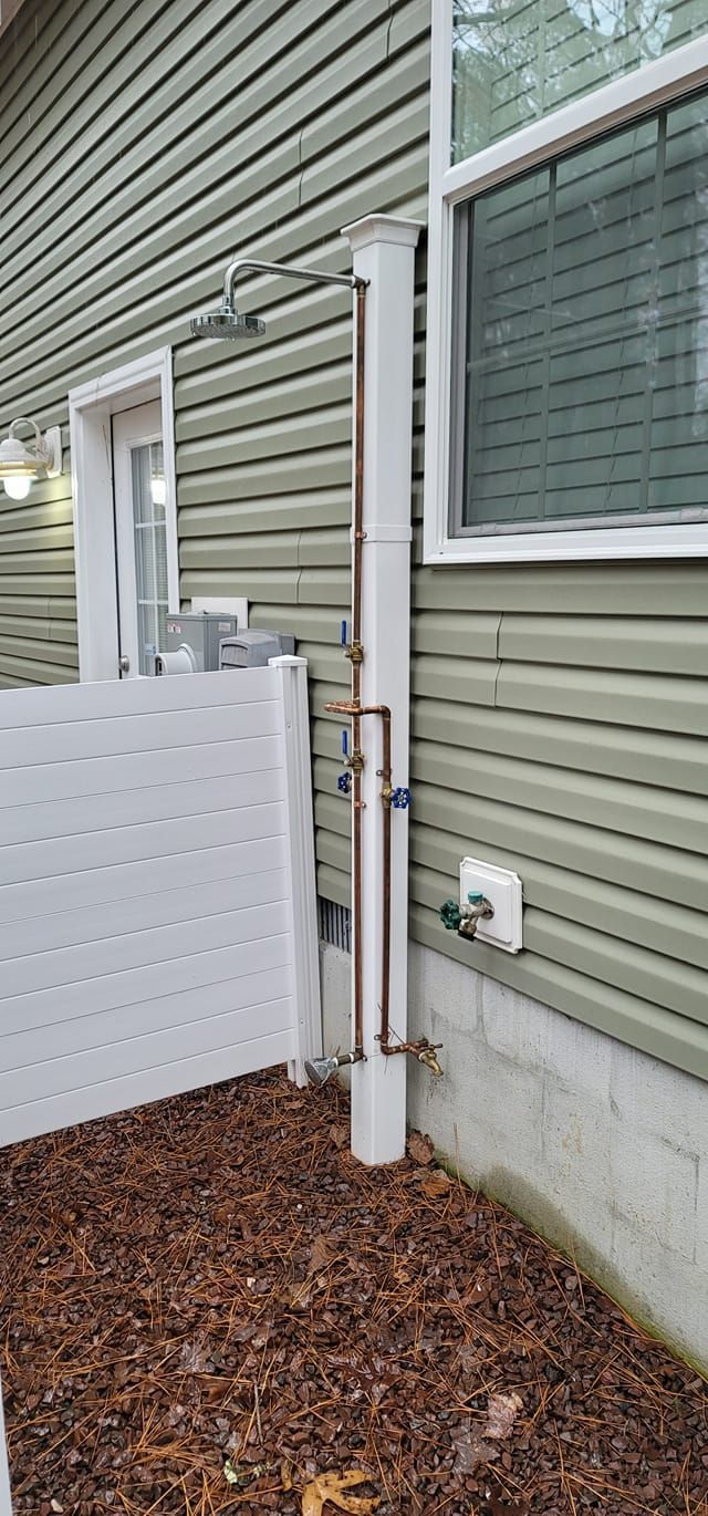 Exterior house wall with utility meters and conduit beside a white fence and window