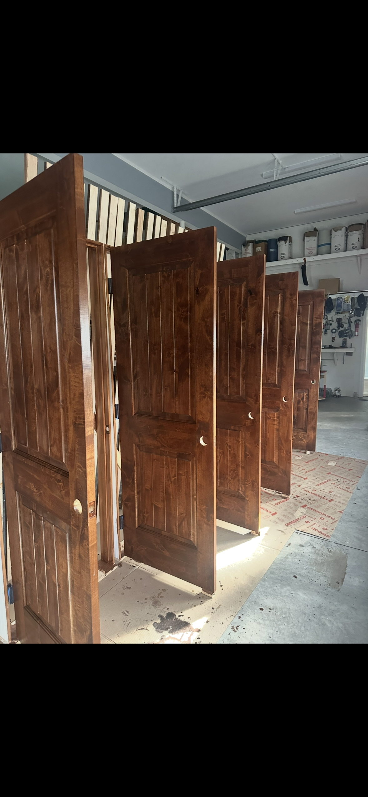 A row of several identical, dark-stained wooden interior doors lined up in a workshop or studio space.