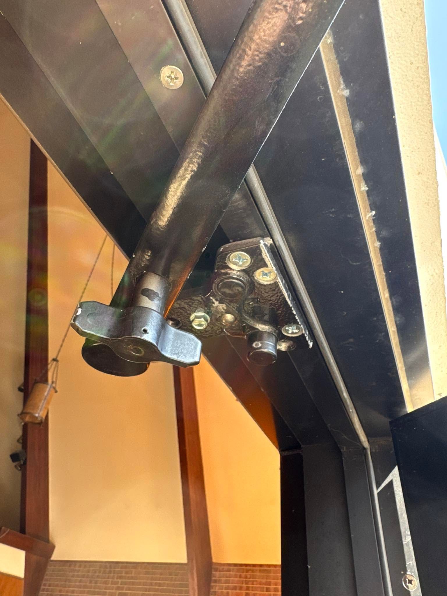 Black metal ceiling beams with a hanging light fixture in an indoor stairwell.