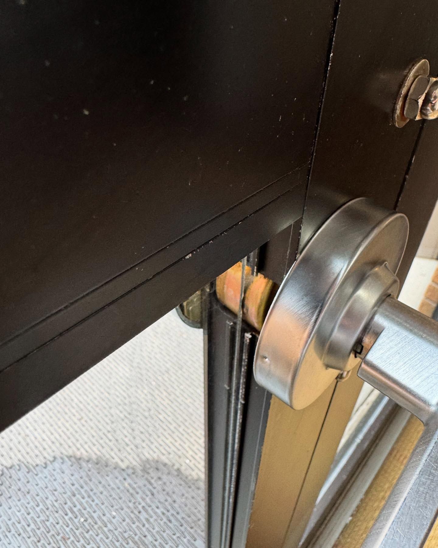 Close-up of a black cabinet door and silver latch mechanism on a metal frame