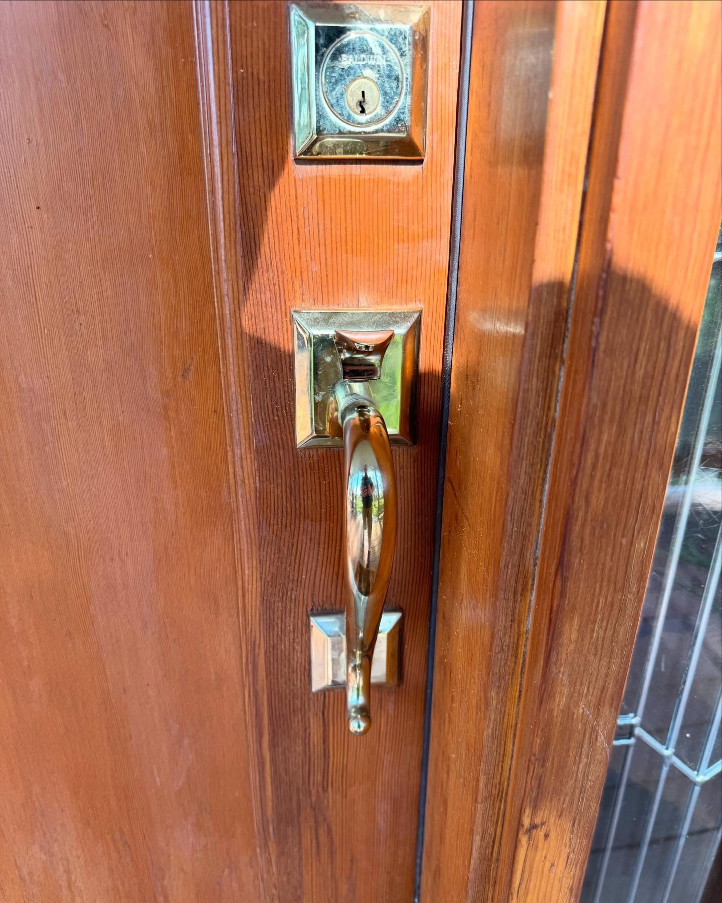 Close-up of a brass front door handle and lock on a wooden door