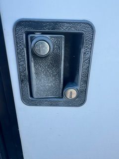 Black recessed door handle with a round lock on a light blue door panel.