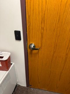 Office hallway with a closed wood door, silver handle, and black wall switch beside it