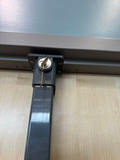 Black metal strap with a silver key lock attached to a wall-mounted fixture.
