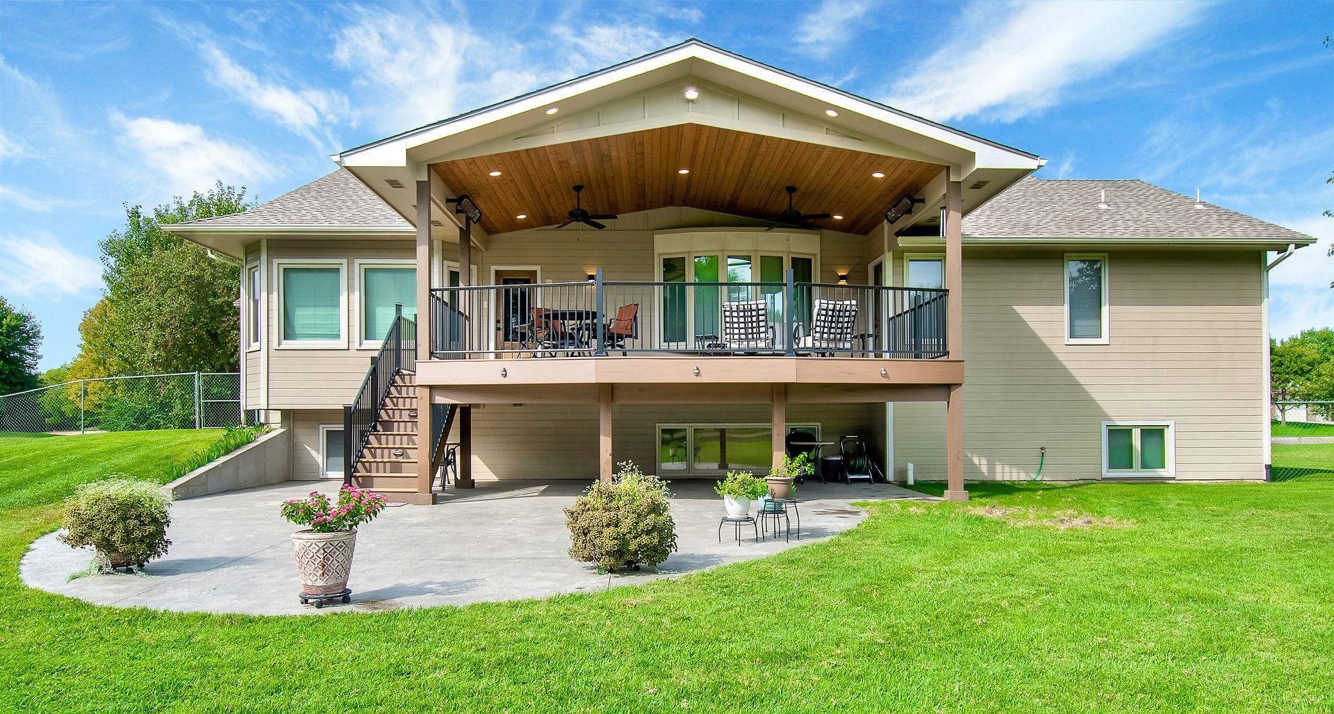 The back of a large house with a large deck and patio.