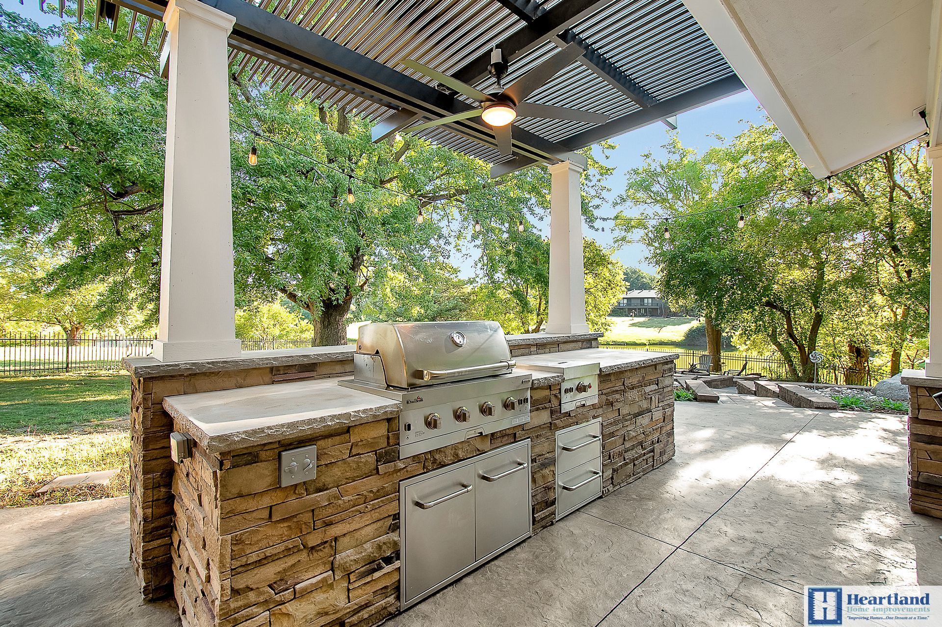 An outdoor kitchen with a grill and a ceiling fan