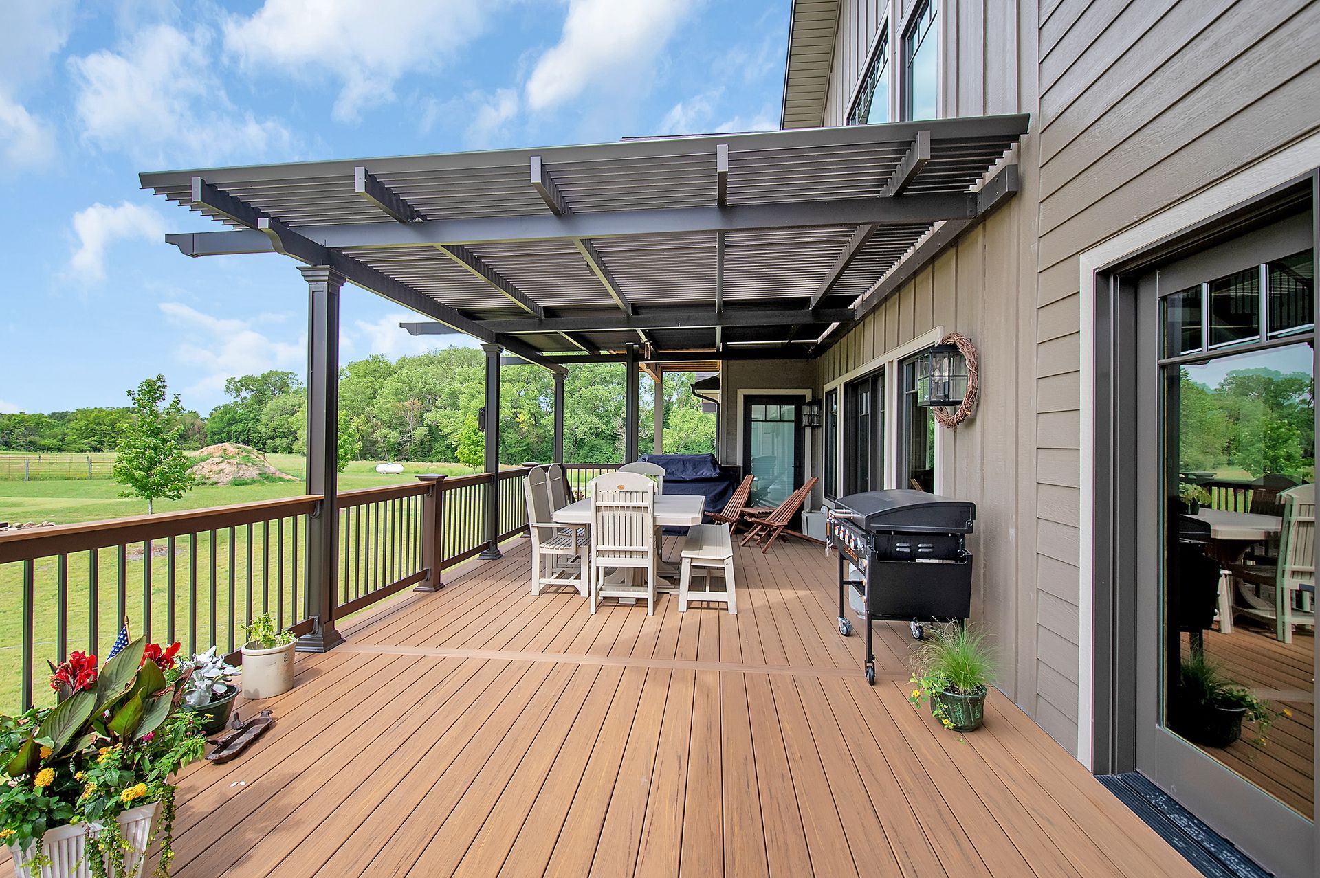 There is a large deck with a pergola and a grill on it.