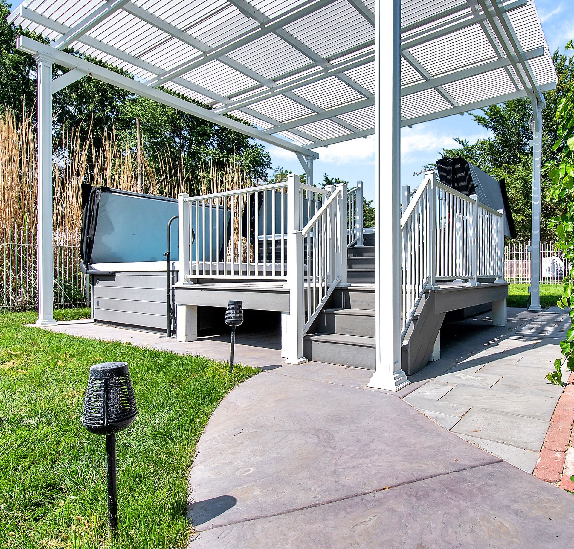 A deck with stairs and a hot tub under a pergola