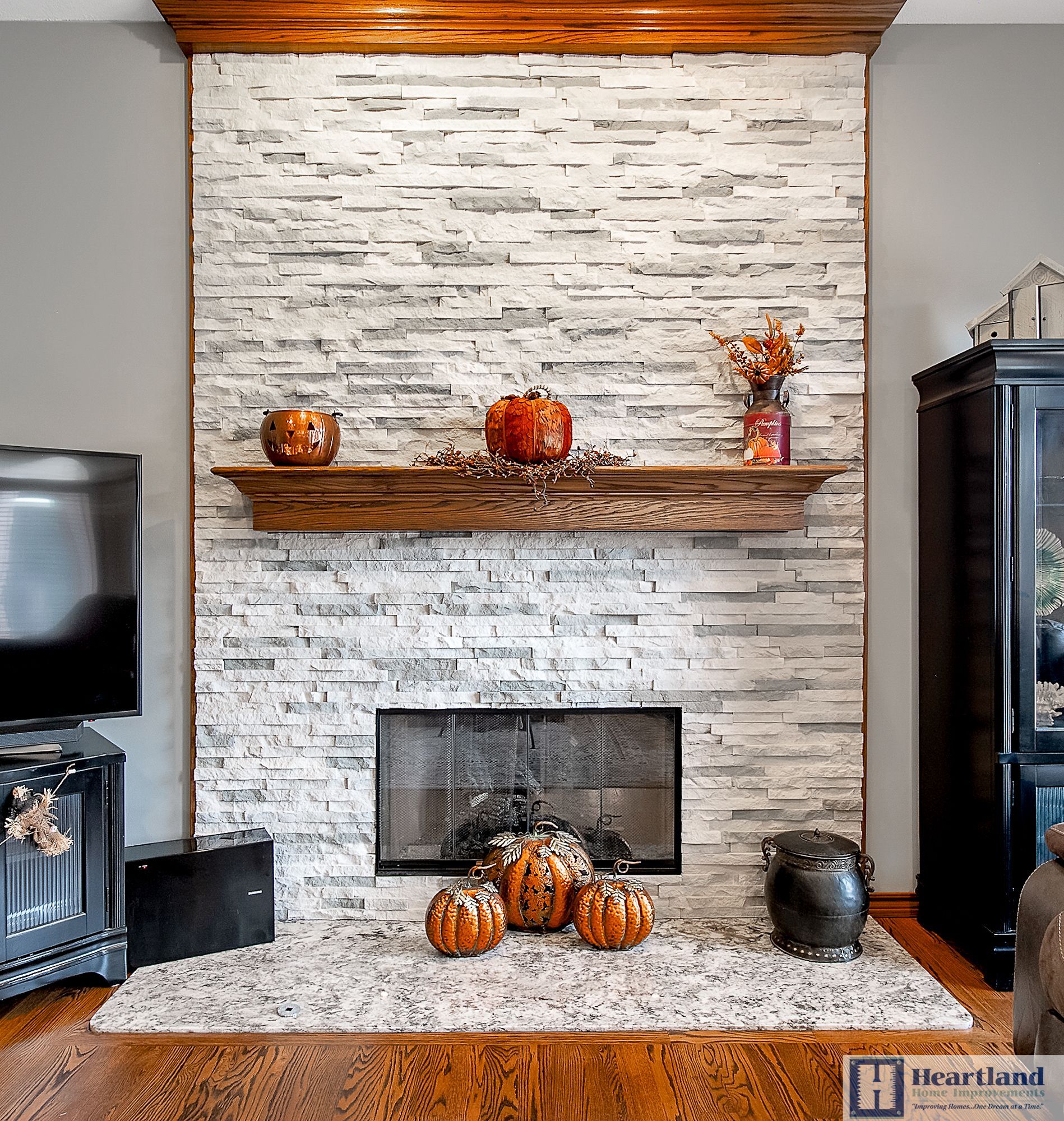 A living room with a fireplace and a shelf with pumpkins on it