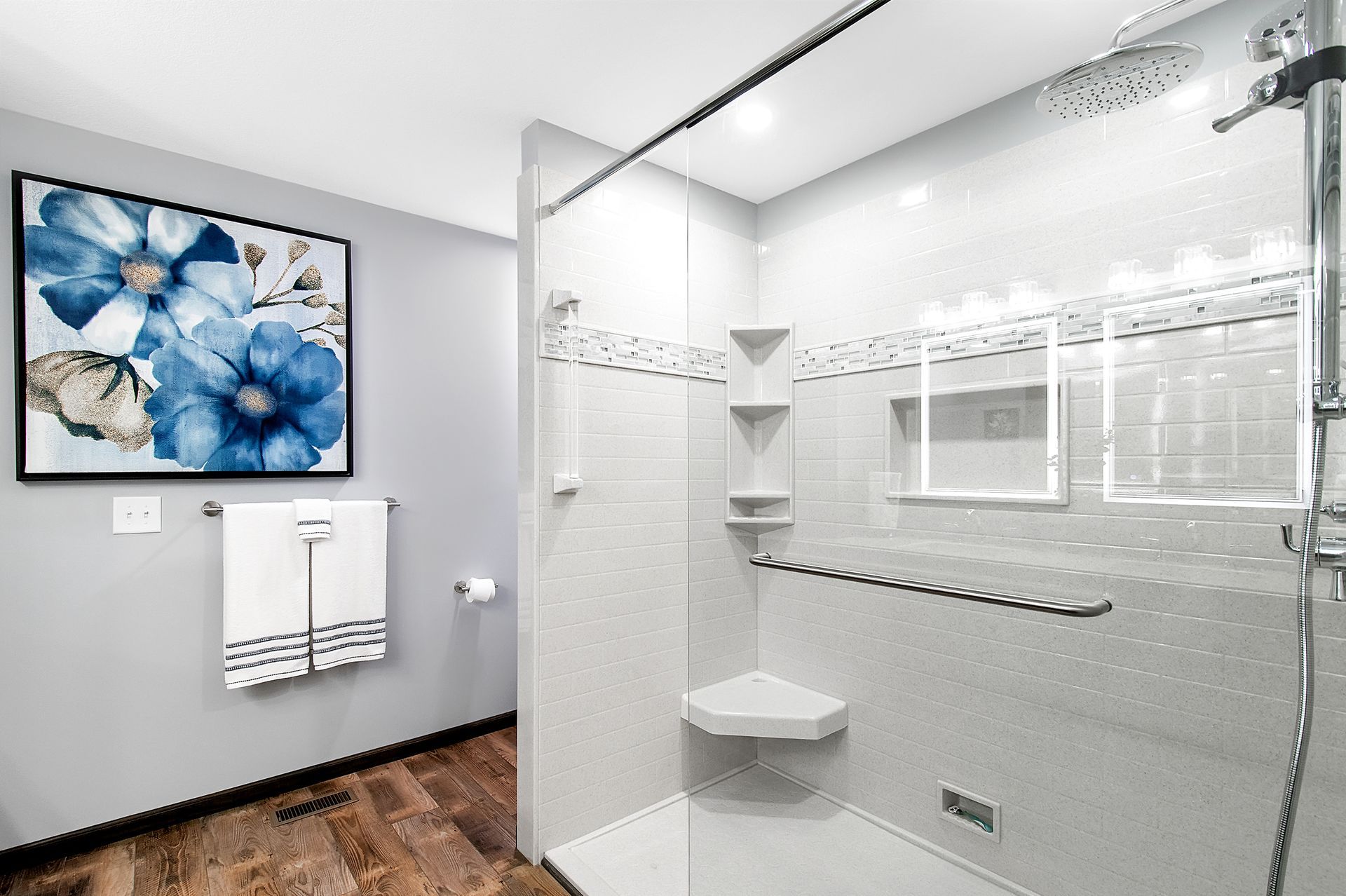 A bathroom with a walk in shower and a picture on the wall.
