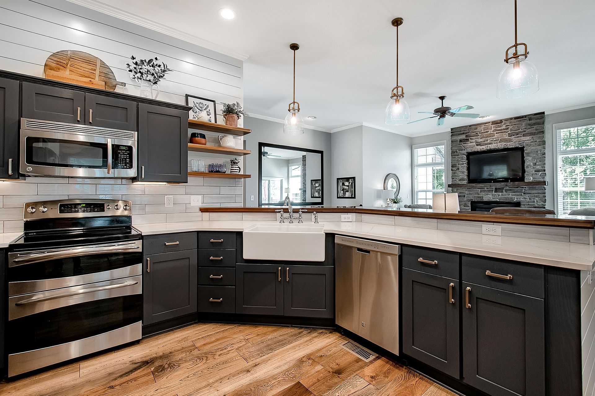 A kitchen with gray cabinets , stainless steel appliances , a sink , and a stove.