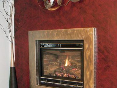 A fireplace with a red wall behind it