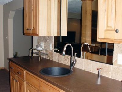 A kitchen counter with a sink and a mirror