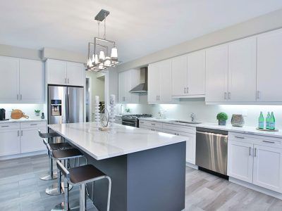 A kitchen with white cabinets , stainless steel appliances , and a large island.