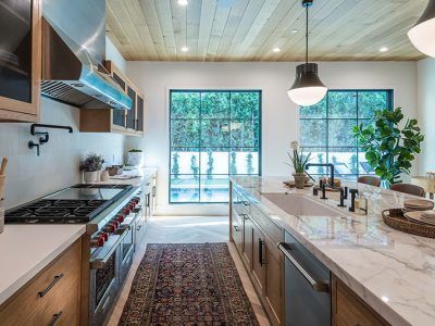 A kitchen with a stove , sink , and a large window.