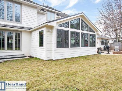 The back of a house with a sunroom and a lot of windows.