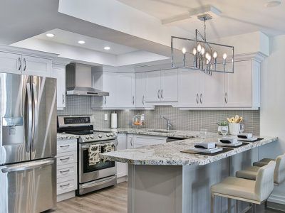A kitchen with white cabinets , stainless steel appliances , granite counter tops and a large island.