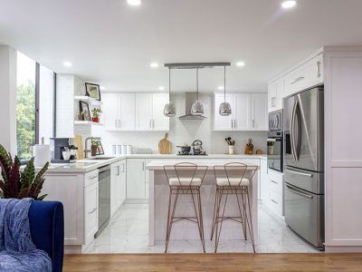 A kitchen with white cabinets , stainless steel appliances , and a large island.