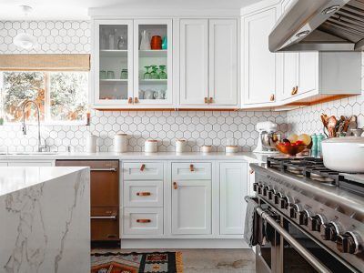 A kitchen with white cabinets , stainless steel appliances , and a stove.