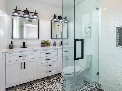 A bathroom with a toilet , sink , mirrors and a walk in shower.