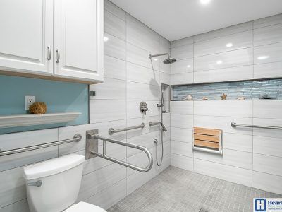 A bathroom with a toilet , shower , and wooden seat.