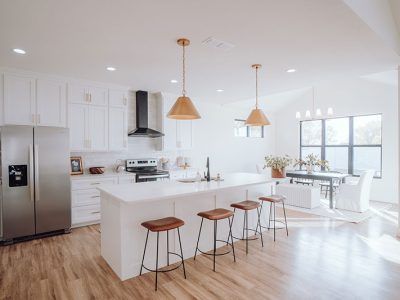 A kitchen with white cabinets , stainless steel appliances , a refrigerator , and a large island.