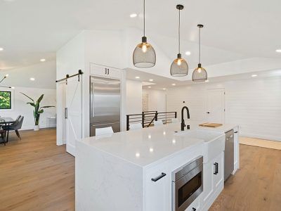 A kitchen with white cabinets , stainless steel appliances , and a large island.
