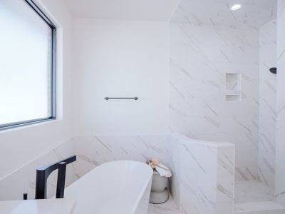 A bathroom with a tub , toilet , shower and window.