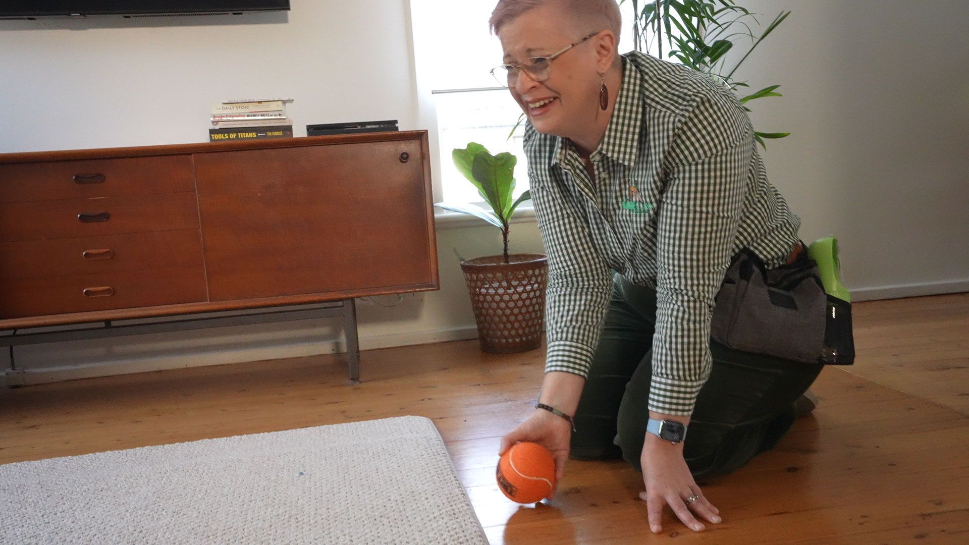 A man is kneeling on the floor holding an orange.