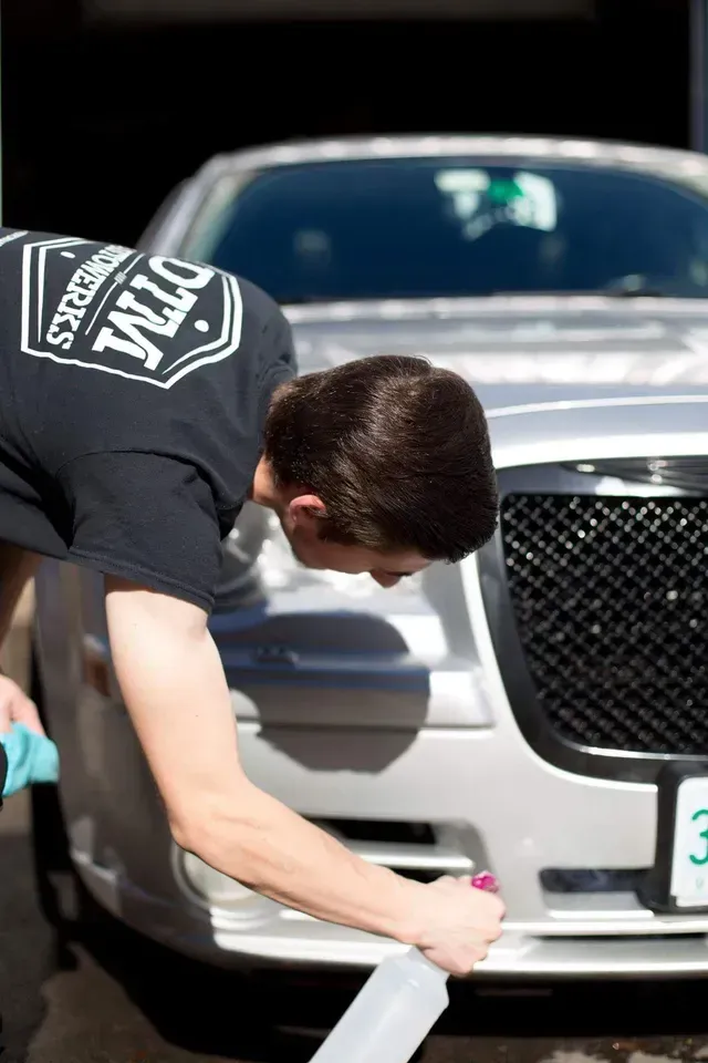 Technician Applying Protective Film On A Vehicle Front End | DTM Autowerks