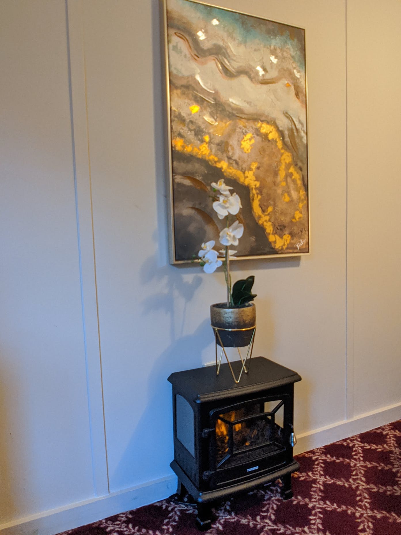A fireplace with a potted plant and a painting on the wall above it.