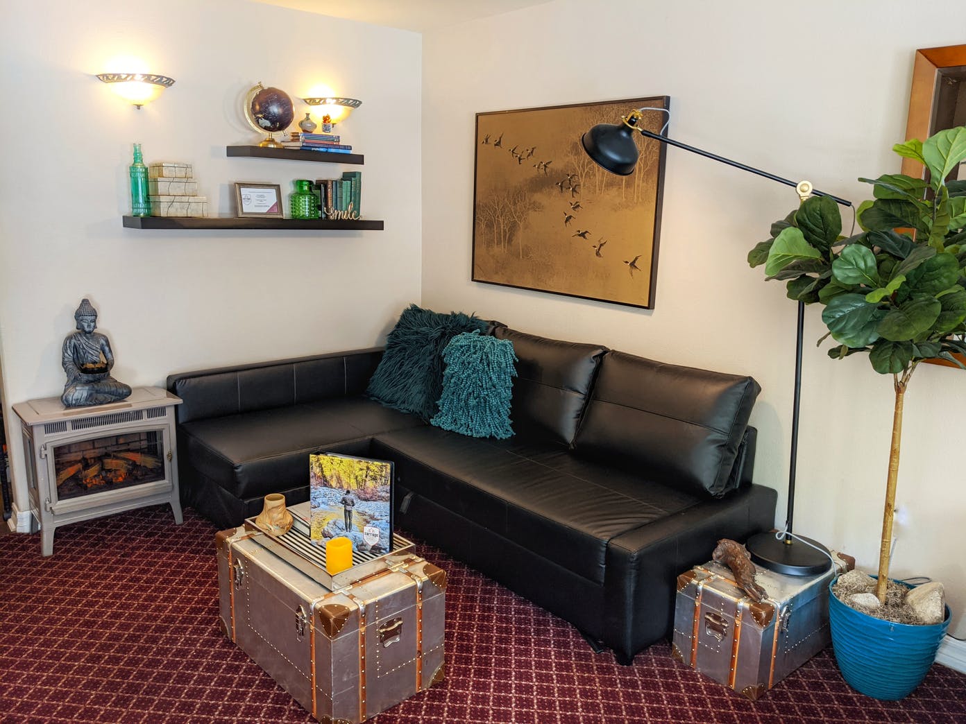 A living room with a black couch , a coffee table , and a fireplace.
