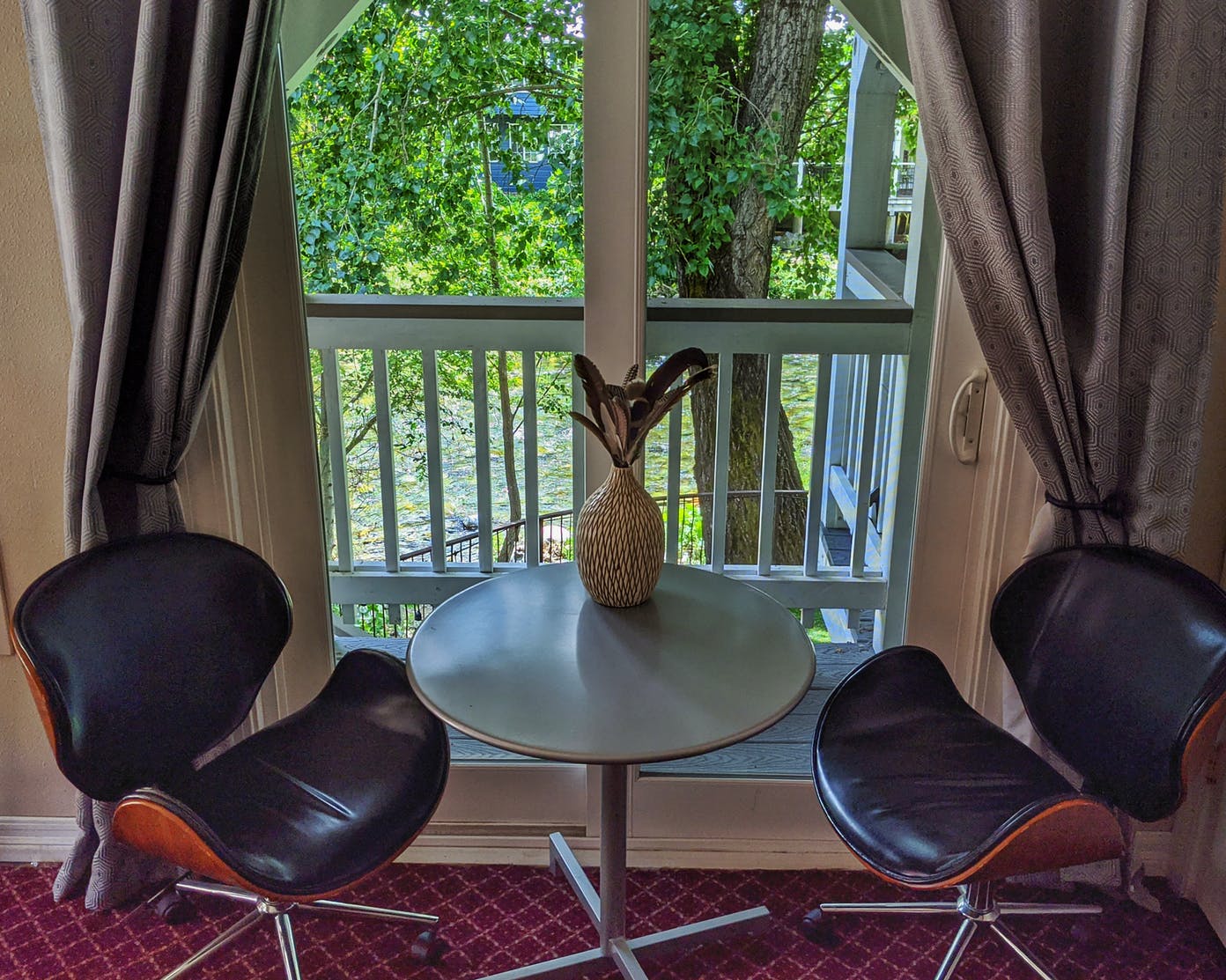 Two chairs and a table in front of a window with a pineapple on it.