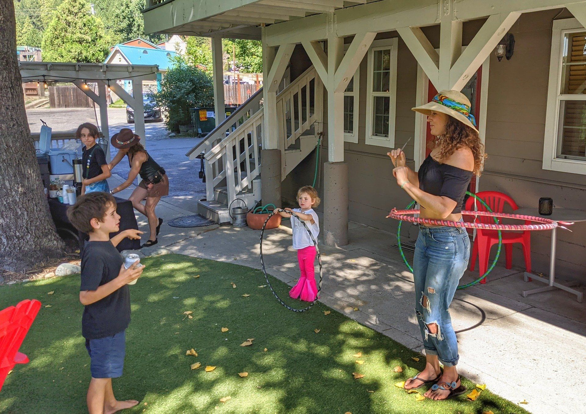 A woman is playing with a hula hoop in front of a house.