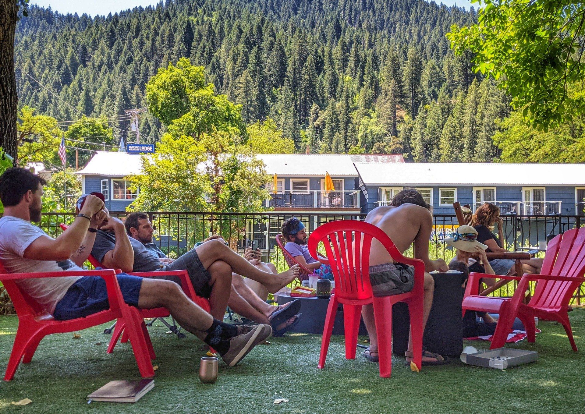 A group of people are sitting in red chairs around a fire pit.