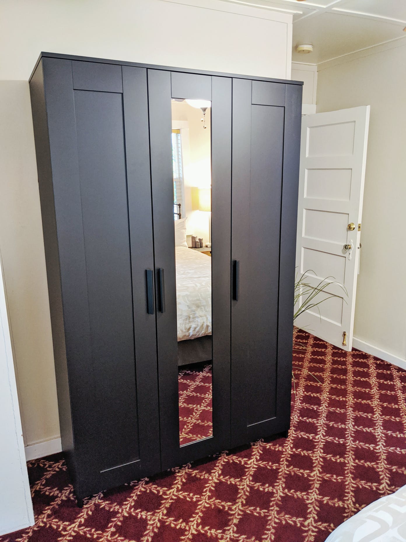 A black wardrobe with a mirror in a bedroom