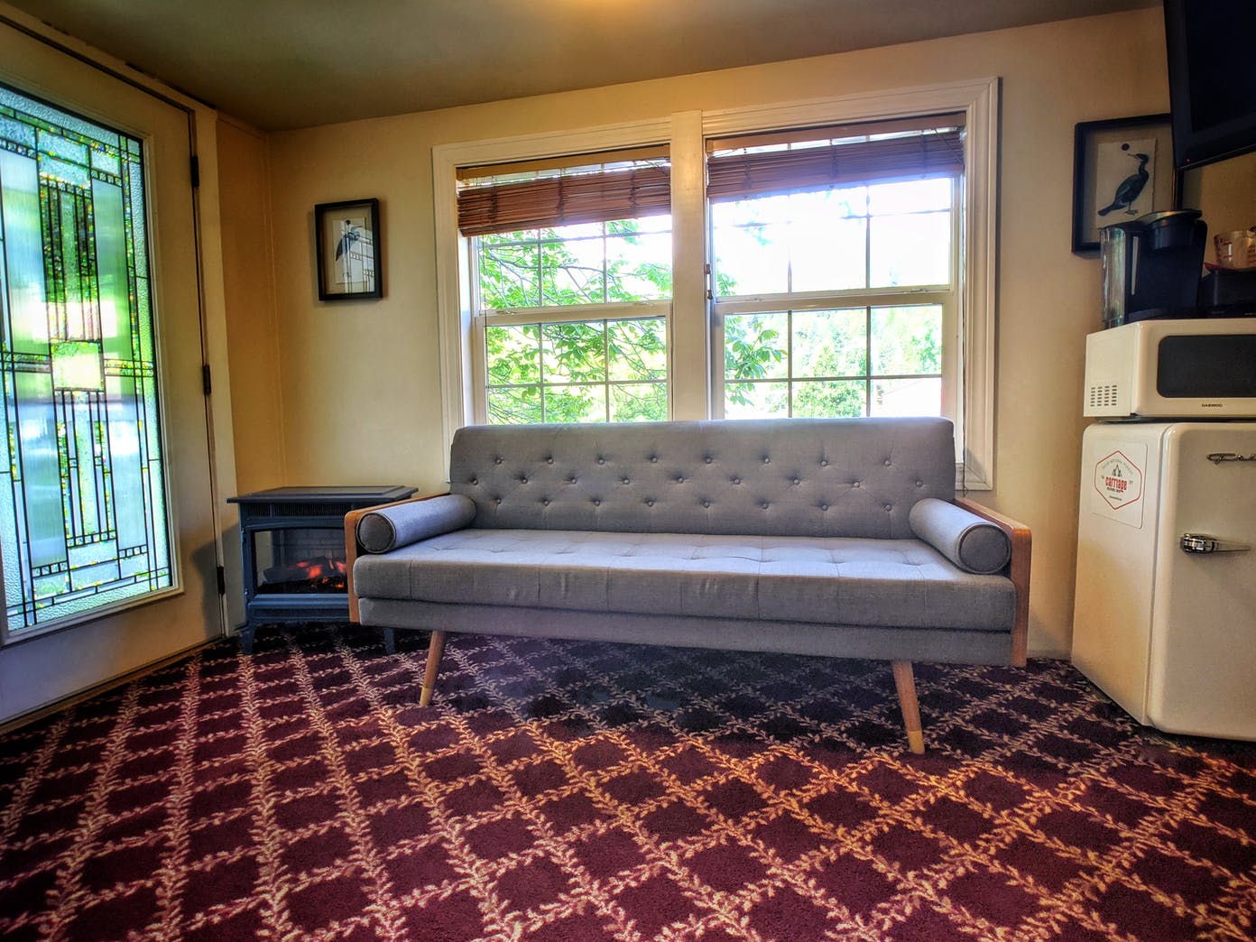 A living room with a couch , fireplace , microwave and refrigerator.