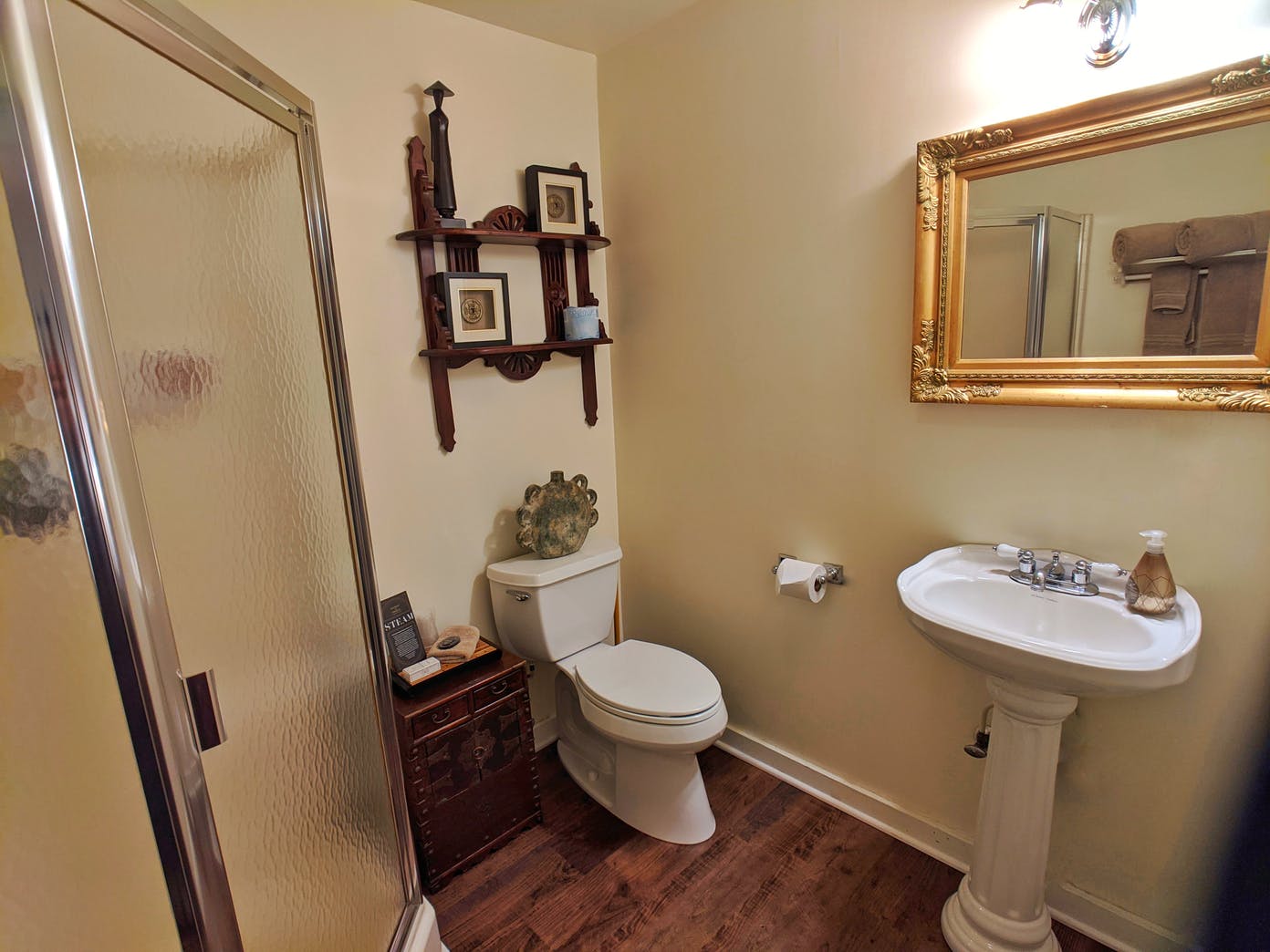 A bathroom with a toilet , sink , shower and mirror