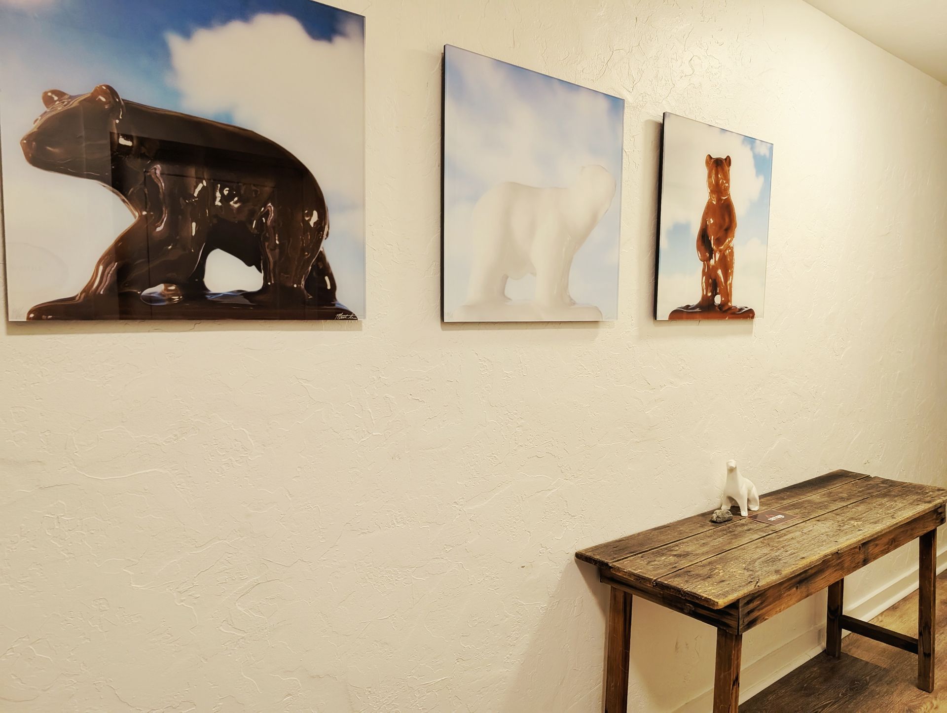 Three pictures of bears are hanging on a wall next to a table