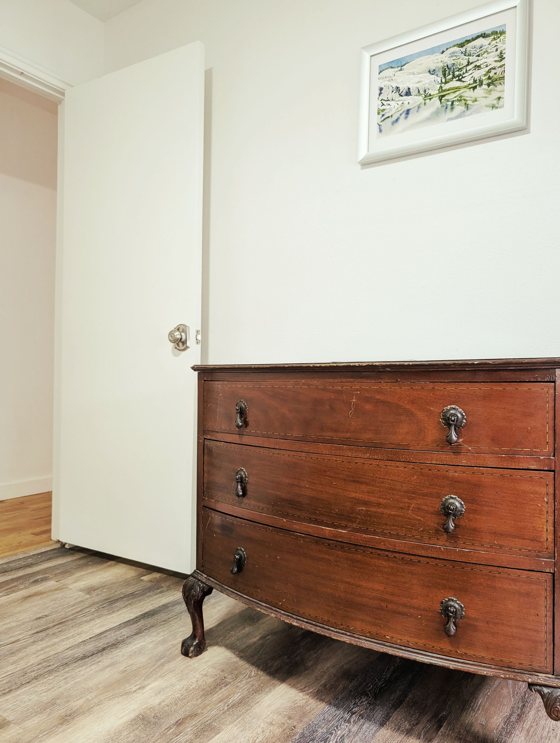 A wooden dresser is sitting in a room next to a door.
