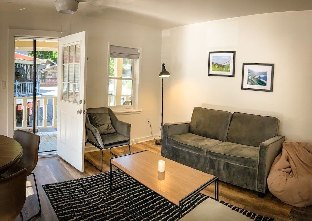 A living room with a couch , chairs , coffee table and rug.