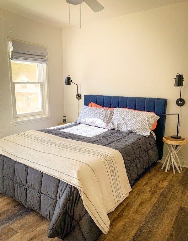 A bedroom with a bed , nightstand , and ceiling fan.