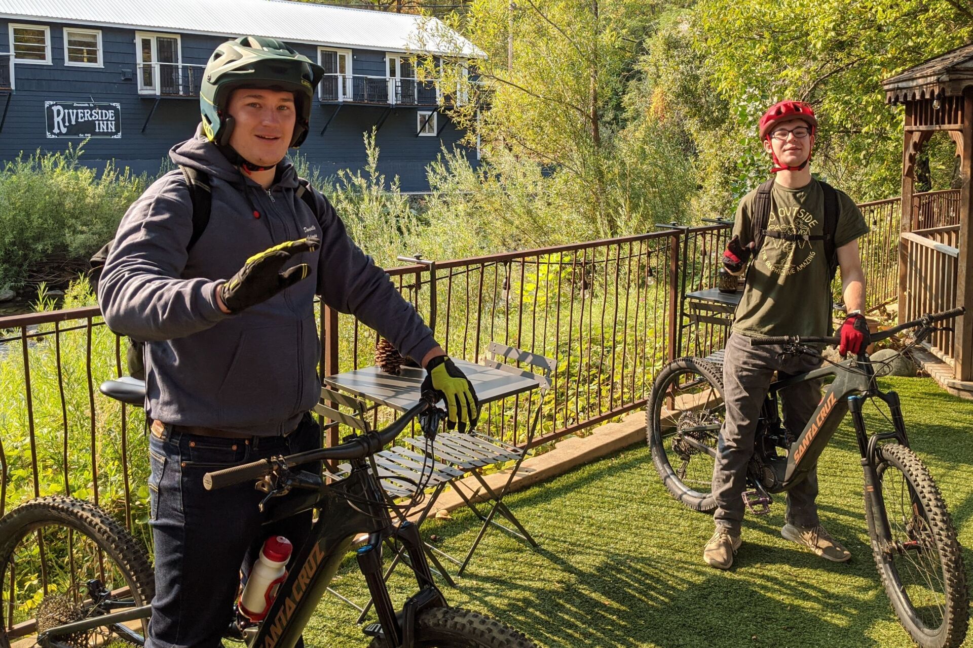Two men are standing next to each other with bicycles in front of a building.