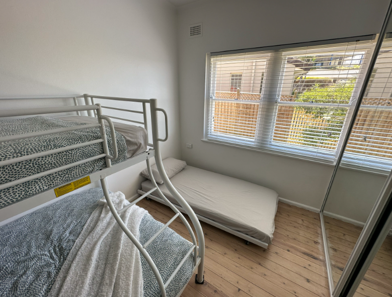 A bedroom with two bunk beds and a single bed.