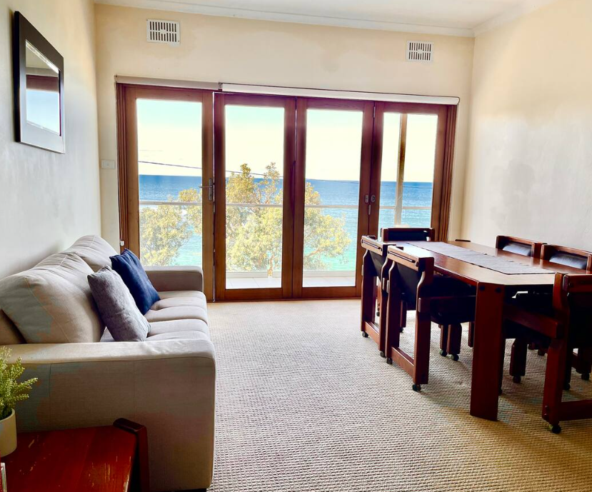 A living room with a couch and a table with a view of the ocean